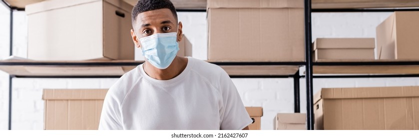 African American Seller In Medical Mask Looking At Camera Near Boxes On Rack In Online Web Store, Banner