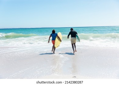 African american senior couple carrying surfboards running towards waves at beach with copy space. unaltered, togetherness, active lifestyle, aquatic sport and holiday concept. - Powered by Shutterstock