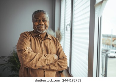 African American Senior Man at home Portrait. Smiling senior man looking at camera. Portrait of black confident man at home. Portrait of a senior man standing against a grey background - Powered by Shutterstock