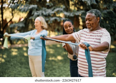 African American senior using resistance band during physical therapy in backyard of a nursing home. - Powered by Shutterstock