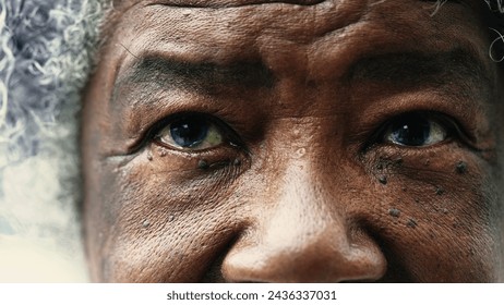 African American senior woman closing eyes in macro tight closeup. Wrinkled elderly lady meditating and praying, opening eyes with HOPE - Powered by Shutterstock