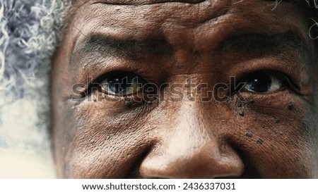 African American senior woman closing eyes in macro tight closeup. Wrinkled elderly lady meditating and praying, opening eyes with HOPE