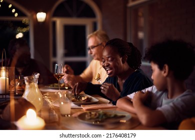 African American Senior Woman Eating While Having Dinner With Her Family At Dining Table On A Patio.