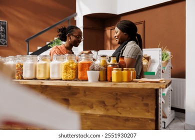 African American shopkeeper and customer surrounded by freshly harvested produce discussing about healthy eating and sustainable lifestyle choices. Vendor showing organic bio food items to client. - Powered by Shutterstock