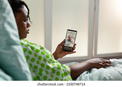 African American Sick Patient Holding Phone Discussing Disease Expertise With Remote Therapist Doctor During Online Videocall Meeting Conference In Hospital Office. Telehealth Call On Screen