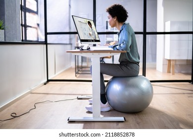 African American Sitting On Exercise Ball At Office Desk