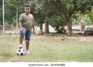 African American slightly overweight boy with soccer ball doing exercise in the park. slightly overweight little kid