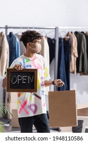 African American Small Business Owner In Protective Mask Holding Chalkboard With Open Lettering And Shopping Bag