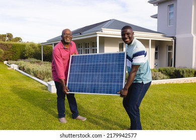 African american smiling senior man and son carrying solar panel while standing on field in yard. House, family, summer, unaltered, solar energy, electricity, retirement and sustainability concept. - Powered by Shutterstock