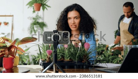 African American smiling woman florist blogger recording floristry video course, conference calling or streaming live creative web training lesson on smart phone. Owner woman using smartphone in