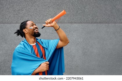 African American Soccer Fan Blowing A Vuvuzela While Cheering For His Favorite Team. Copy Space.