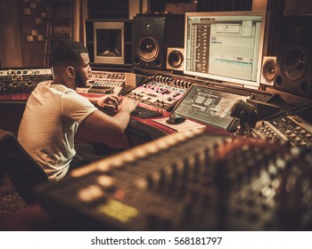 African American Sound Engineer Working At Mixing Panel In Boutique Recording Studio.