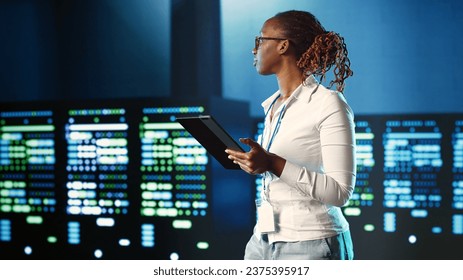 African american specialist strolling through server rows providing processing resources for different workloads. Experienced woman monitoring supercomputers tasked with solving complex operations