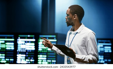 African american specialist using tablet to check data center security features protecting against unauthorized access, data breaches, DDoS attacks and other cybersecurity threats - Powered by Shutterstock