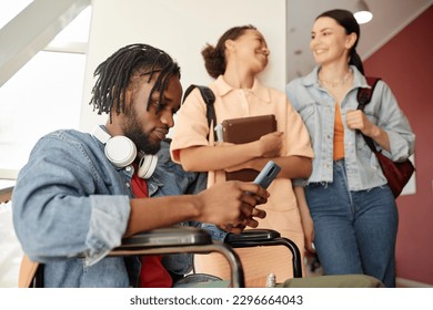 African American student with disability sitting on wheelchair and using smartphone during break at college - Powered by Shutterstock