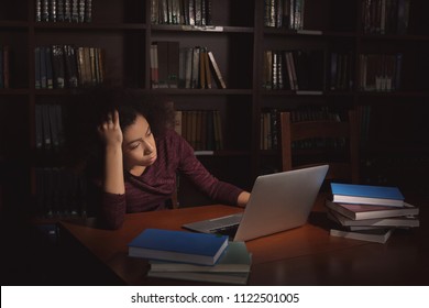 African American Student With Laptop Studying In Library Late At Night