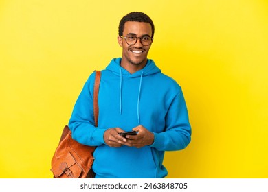 African American student man over isolated yellow background surprised and sending a message - Powered by Shutterstock