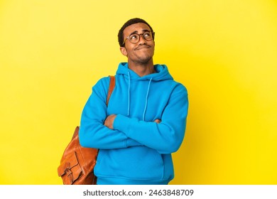 African American student man over isolated yellow background looking up while smiling - Powered by Shutterstock