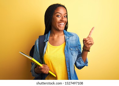 African American Student Woman Wearing Backpack And Book Over Isolated Yellow Background Very Happy Pointing With Hand And Finger To The Side