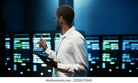 African american supervisor in server farm using tablet to find firewall misconfigurations affecting rackmounts performance and connectivity, leading to slow data transfer rates - Powered by Shutterstock