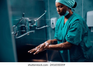 African American surgeon preparing for operating room while washing her hands at medical clinic. Copy space. - Powered by Shutterstock