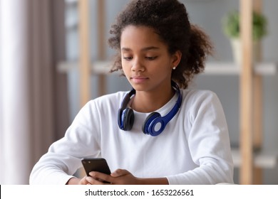 African american teen girl with headphone search music in mobile app, teenage school student holding smartphone using phone application, playing game, chat in messenger social media, texting message