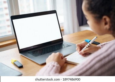 African American Teen Girl Watch Studying Online Using Applications, App, E Learning Distance Training Course At Home. Over Shoulder View On Mockup Image On Laptop Computer With White Screen.