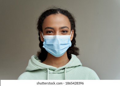 African American Teen Girl Wearing Face Mask Looking At Camera Isolated On Grey Background. Mixed Race Teenager During Coronavirus. Children Safety For Covid Protection, Close Up Headshot Portrait.