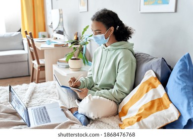 African American Teen Girl Wears Face Mask Distance Learning Online At Home. Ill Mixed Race Teenager Watching Webinar, Virtual School Lesson, Digital Class Using Laptop Studying During Covid Pandemic.