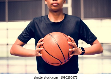 African American teenage boy holding a basketball on the court