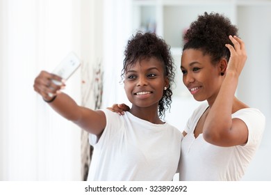 African American teenage girls taking a selfie picture with a smartphone - Shutterstock ID 323892692