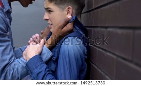 African american teenager bullying weak boy, intimidating with physical abuse