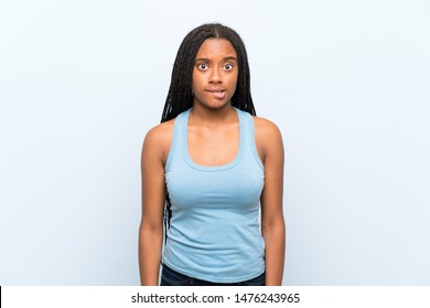 African American teenager girl with long braided hair over isolated blue background having doubts and with confuse face expression