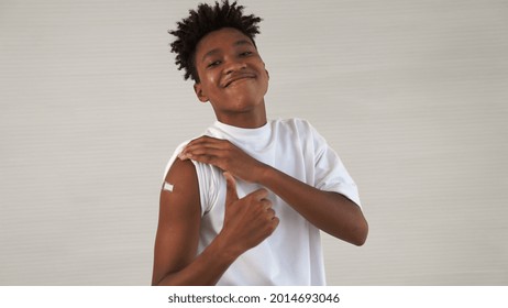 African American teenager showing COVID-19 vaccine bandage merrily in concept of coronavirus vaccination program to vaccinate citizen . - Powered by Shutterstock