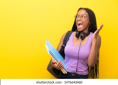 African American Teenager Student Girl With Long Braided Hair Over Isolated Yellow Wall With Surprise Facial Expression