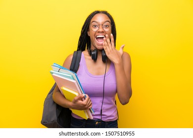 African American Teenager Student Girl With Long Braided Hair Over Isolated Yellow Wall With Surprise Facial Expression