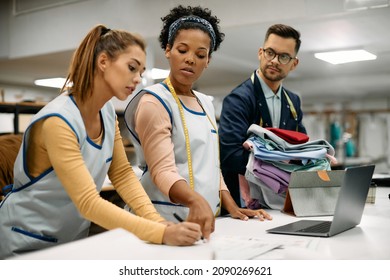 African American textile worker and her colleagues working on new project in clothing design studio. - Powered by Shutterstock