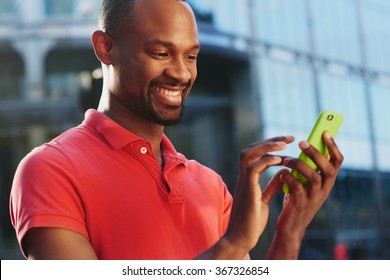 African American Using Smart Phone In Busy City To Stay Connected Using Social Media