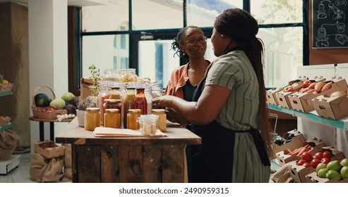 African american vendor giving food sample to shopper, recommending homemade snacks with organic ingredients. Vegan client trying out grocery store products before buying. Handheld shot. - Powered by Shutterstock