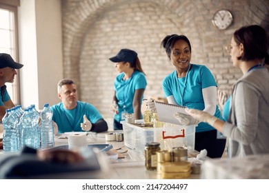 African American volunteer going through donation checklist while talking to her associate at food bank. - Powered by Shutterstock