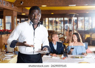 Camarero afroamericano expresando disgusto con Pequeña propina en restaurante