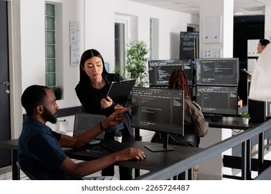 African american web developer using computer to write code and develop algorithm program in big data office room. System engineers working on user interface with html script and terminal window.