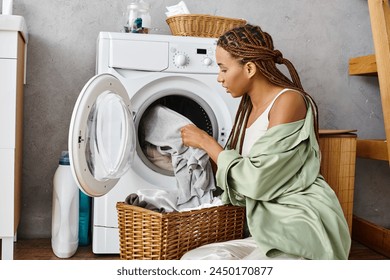 African American woman with afro braids sitting by a washing machine doing laundry in a bathroom. - Powered by Shutterstock