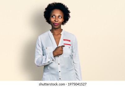 African American Woman With Afro Hair Wearing Hello My Name Is Sticker Identification Smiling Looking To The Side And Staring Away Thinking. 