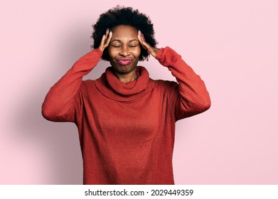 African american woman with afro hair wearing turtleneck sweater suffering from headache desperate and stressed because pain and migraine. hands on head. 