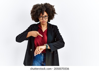 African american woman with afro hair wearing business jacket and glasses in hurry pointing to watch time, impatience, upset and angry for deadline delay 