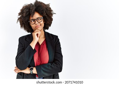 African american woman with afro hair wearing business jacket and glasses thinking worried about a question, concerned and nervous with hand on chin 