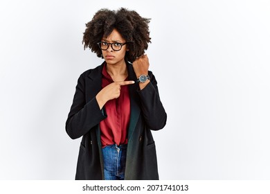 African american woman with afro hair wearing business jacket and glasses in hurry pointing to watch time, impatience, looking at the camera with relaxed expression