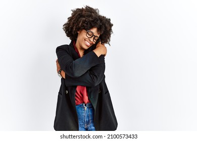 African American Woman With Afro Hair Wearing Business Jacket And Glasses Hugging Oneself Happy And Positive, Smiling Confident. Self Love And Self Care 