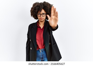 African american woman with afro hair wearing business jacket and glasses doing stop sing with palm of the hand. warning expression with negative and serious gesture on the face. 